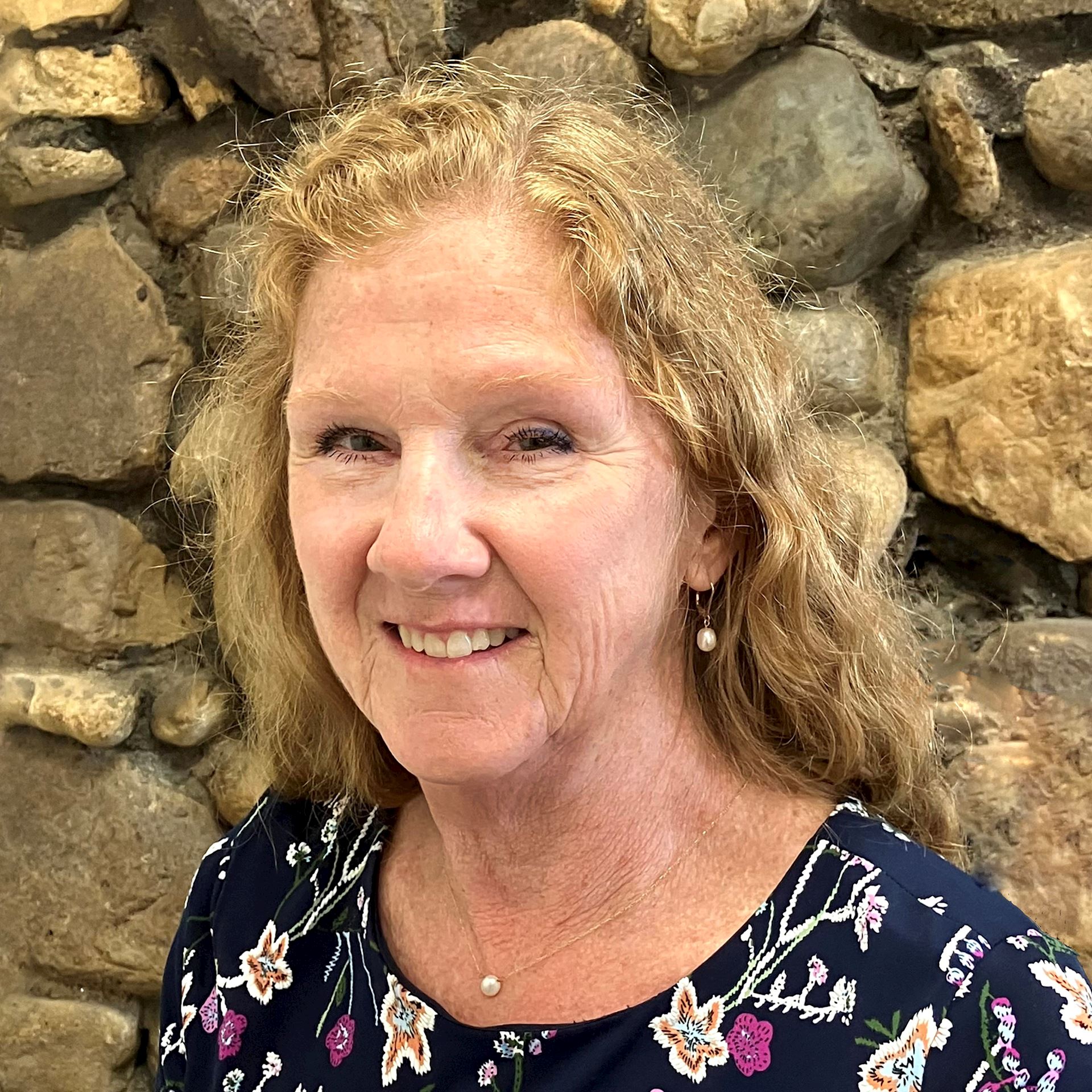 Mary Aiello in front of stone wall.